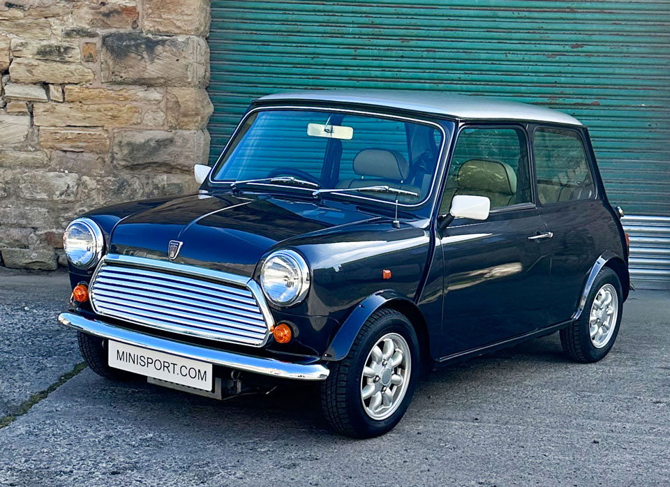 Passenger side front angled view of 1997 Rover Mini, highlighting its sleek Anthracite Black color with silver roof and distinctive white mirrors