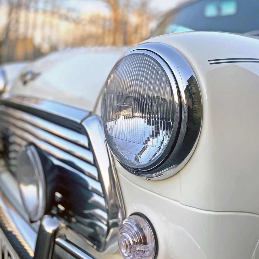 Chrome headlight, and shiny grille on a classic Mini Cooper.