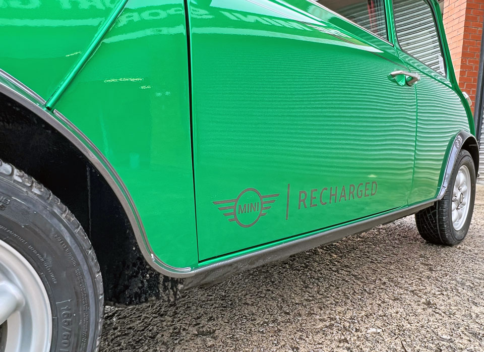 Close-up of MINI Recharged decals on 1995 Mini Cooper EV, highlighting its electric powertrain and eco-friendly features.