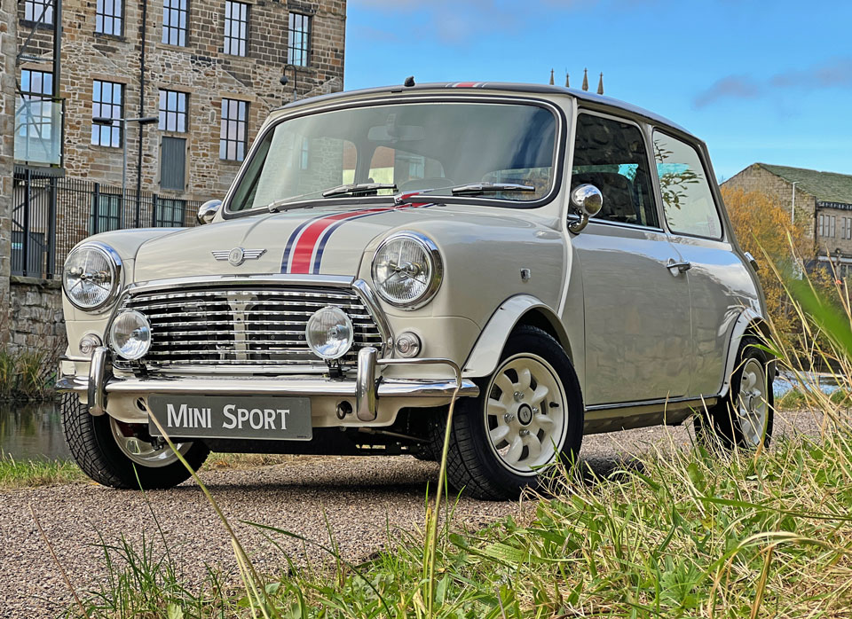 Low down angle front view of 'Merlin' Mini Sport Classic Mini EV, capturing its sleek profile and modern features.