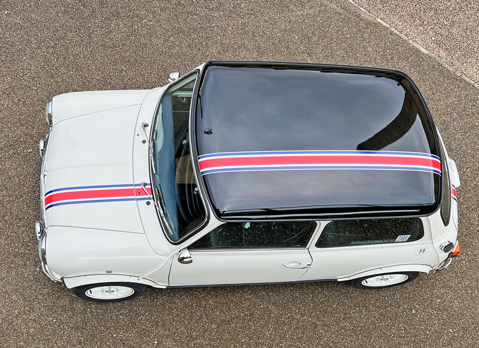 Aerial view of 1999 Rover Mini Cooper 40 EV 'Merlin' with iconic red, blue, and white stripe, showcasing its sporty heritage.
