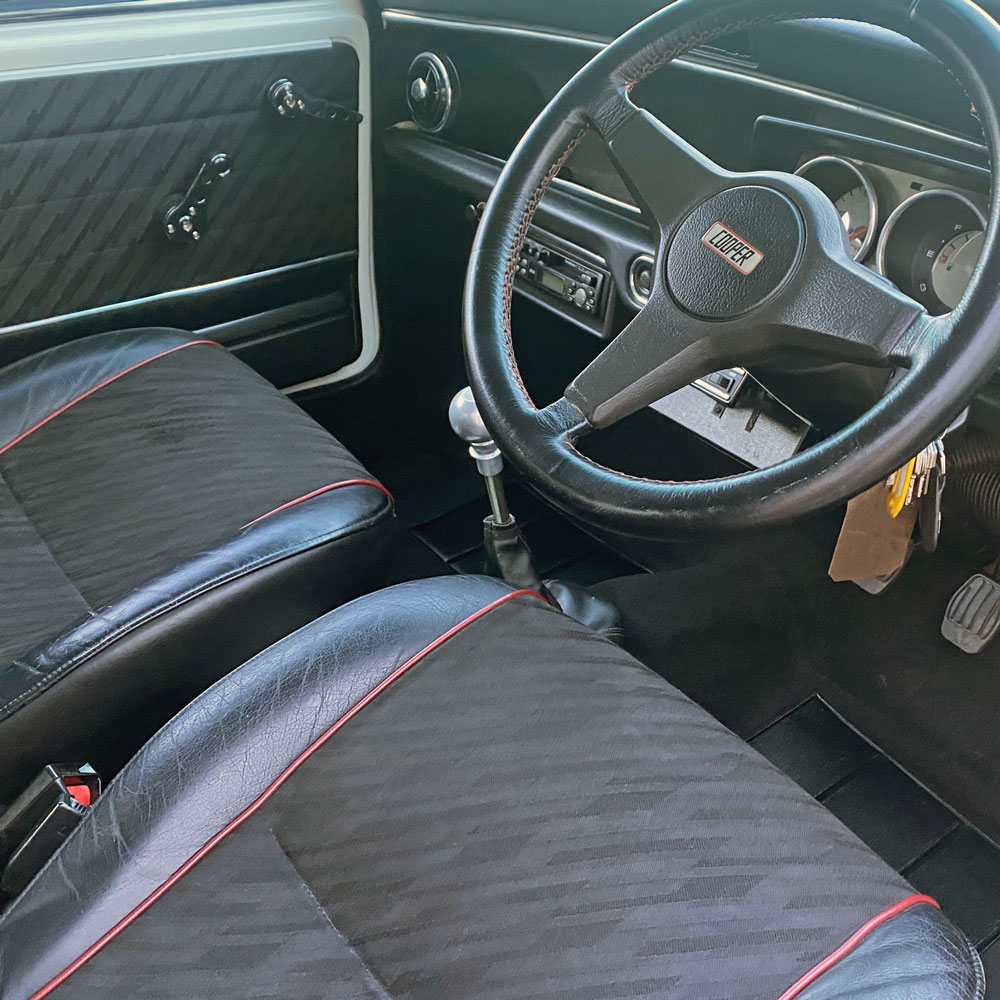 Interior of a classic Mini Cooper, with the original Mini Cooper steering wheel.