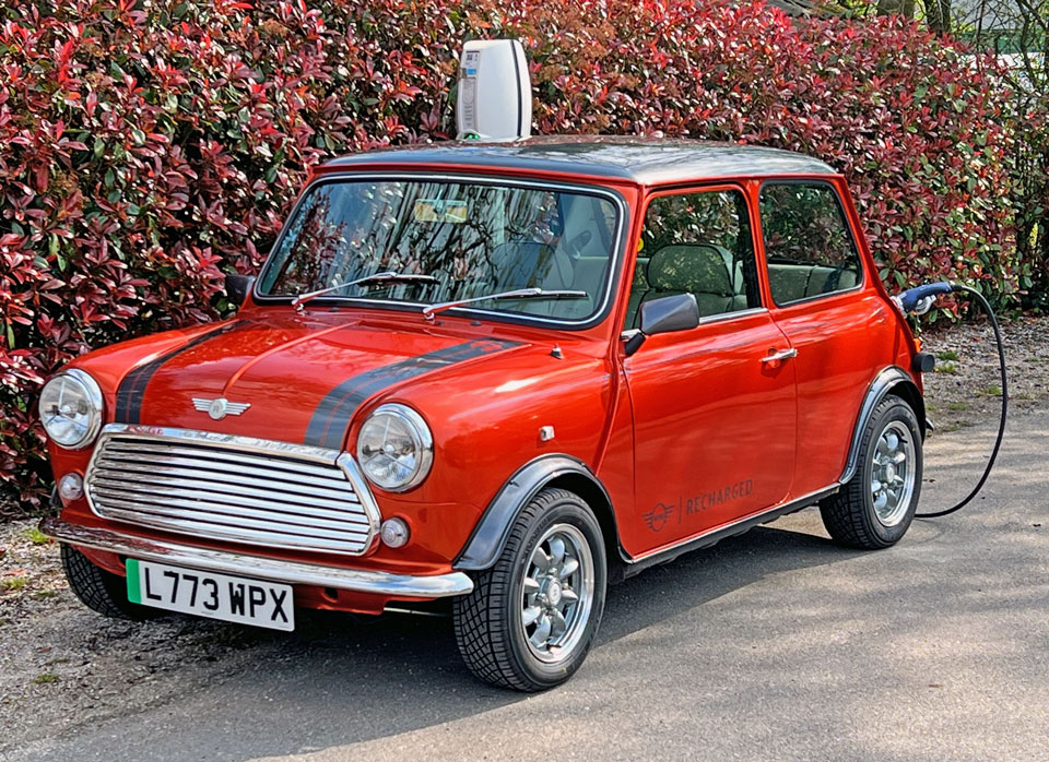 Passenger side front angled view of the Mini Cooper EV, showcasing its electric system while charging