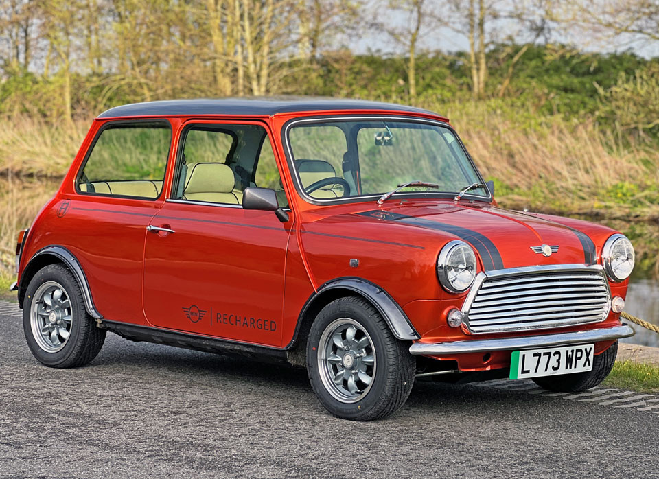 Driver's side front angled view of the stunning Mini Cooper EV, featuring its vibrant orange colour with a sleek black roof