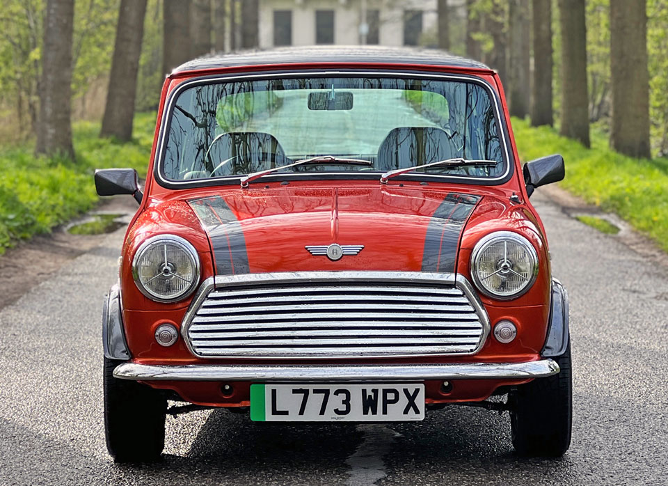 Front view of the Mini Cooper EV, displaying its sleek silhouette and vibrant orange colour