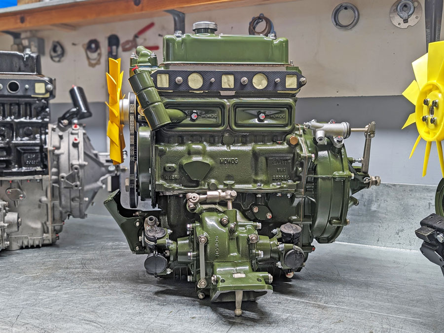 A green remanufactured Mini Engine, on a workbench.