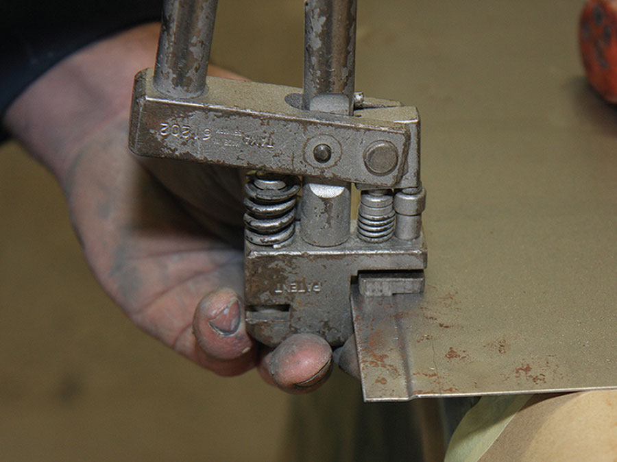 A tool called a "joddler" being used to create a step in the edge of a classic Mini panel for a secure join during body repair.