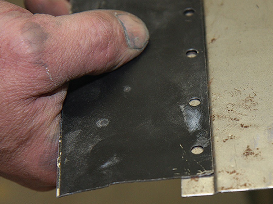 Close-up view of a joddling tool punching holes in a classic Mini panel for potential plug welding during body repair.