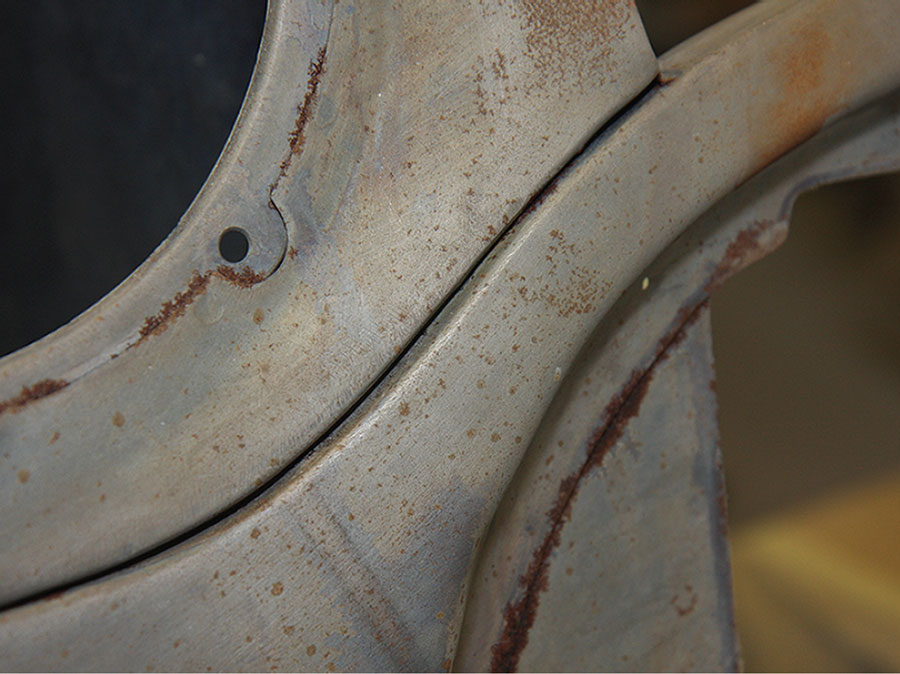 Close-up view of a seam on a classic Mini's front wing, highlighting the area that requires sealing to prevent rust.