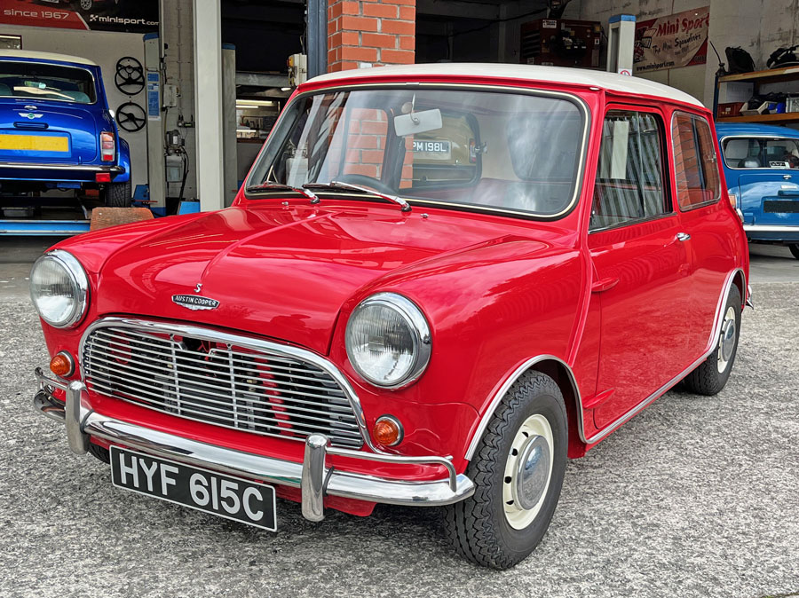 Front passenger side view of a 1965 Austin Mini Cooper S in tartan red with a white roof.
