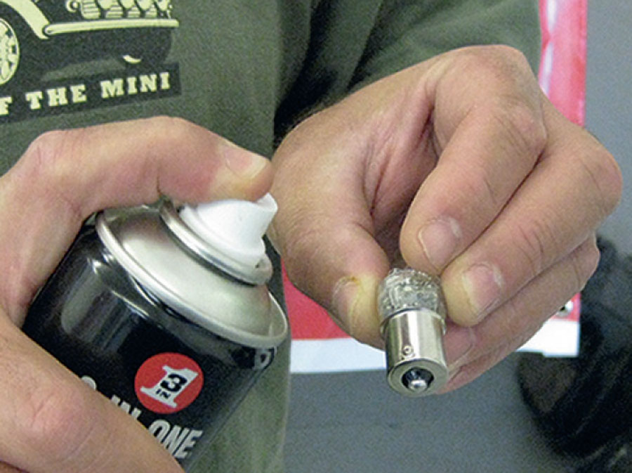 Greasing the metal contact surfaces of Mini indicator lamps to prevent rust and ease removal."