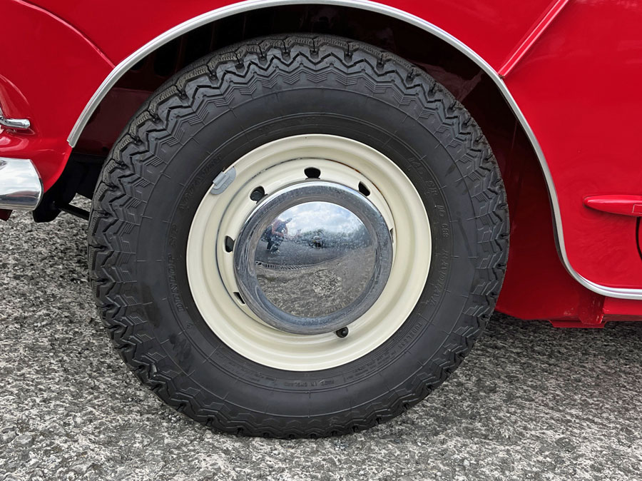 Close-up of MK1 Old English white wheels on a 1965 Austin Mini Cooper S in tartan red