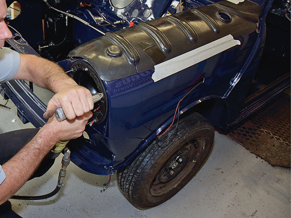 Close-up of pop riveting the shell to secure the headlight bowl on the Mini.