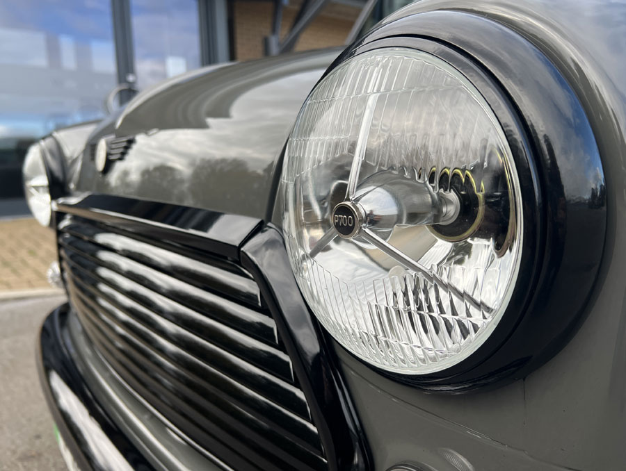 'Spectre' the bespoke Classic Mini EV by Mini Sport, finished in Yukon Grey with a black roof, close up of head lights