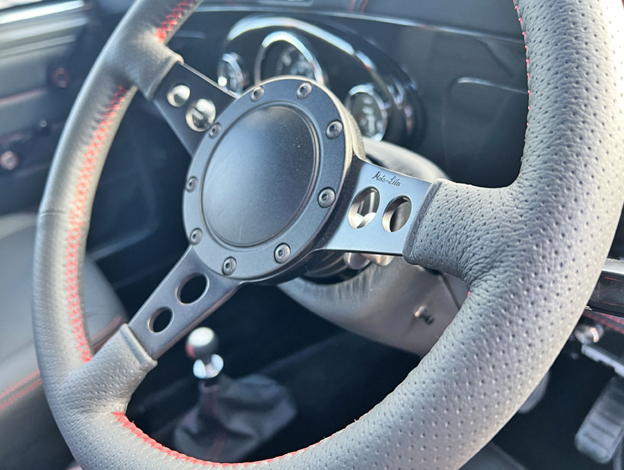 'Spectre' the bespoke Classic Mini EV close up of black leather with red stitching bespoke steering wheel