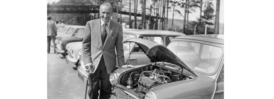 Alec Issigonis with a classic Mini with the bonnet up.